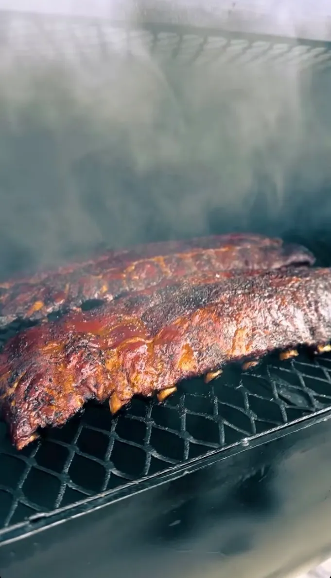 Dos costillares glaseados en la parrilla del ahumador, envueltos en humo