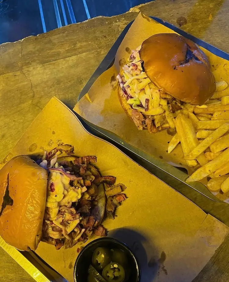 Sándwiches de pulled pork con ensalada de col y papas fritas sobre papel kraft